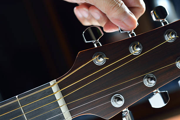 Hand tuning a guitar - adjusting the tuning pegs